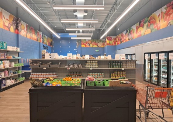 A small single room store with food on shelves and in fridges.