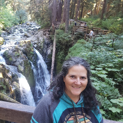Beth smiling at the camera while on a hike near a waterfall.