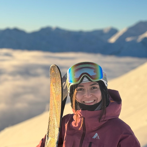 Brenda holding her skis on a mountain.