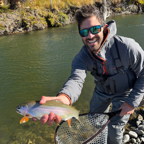 Tom smiling at the camera while holding a fish.